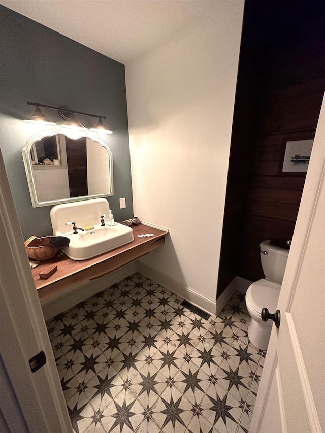 bathroom with toilet, tile flooring, and sink