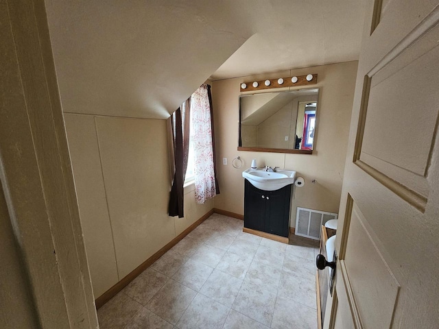 bathroom with vanity, vaulted ceiling, and a healthy amount of sunlight