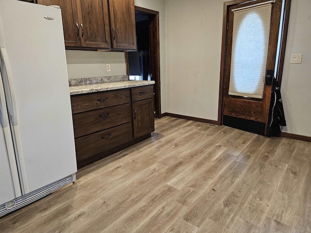 kitchen featuring dark brown cabinets, white refrigerator, and light wood-type flooring