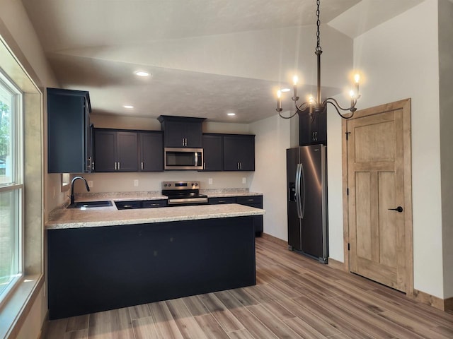 kitchen with kitchen peninsula, appliances with stainless steel finishes, vaulted ceiling, sink, and pendant lighting