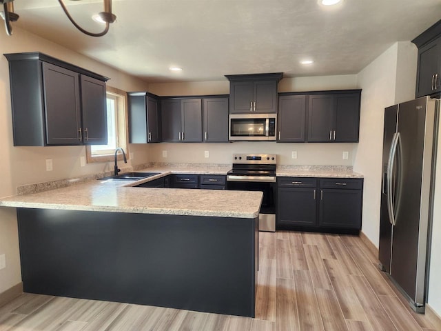 kitchen featuring sink, stainless steel appliances, light stone counters, light hardwood / wood-style floors, and kitchen peninsula