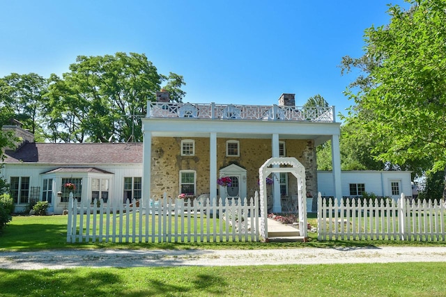 view of front facade with a balcony and a front yard