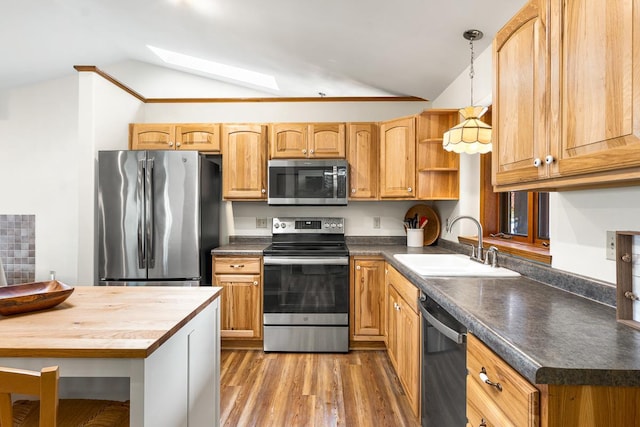 kitchen featuring lofted ceiling with skylight, hanging light fixtures, stainless steel appliances, and hardwood / wood-style floors