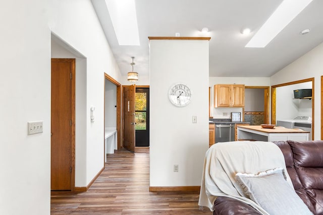 living room featuring lofted ceiling with skylight, independent washer and dryer, and light hardwood / wood-style floors