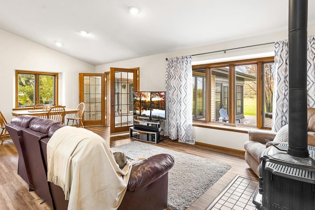 living room with lofted ceiling, a wood stove, and light hardwood / wood-style floors