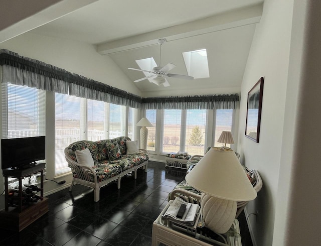 living room featuring lofted ceiling with skylight, dark tile flooring, and ceiling fan