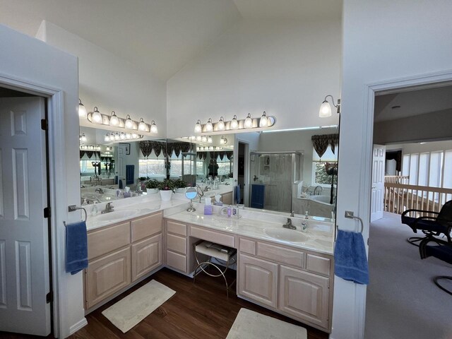 bathroom with a shower with shower door, hardwood / wood-style flooring, high vaulted ceiling, and double vanity