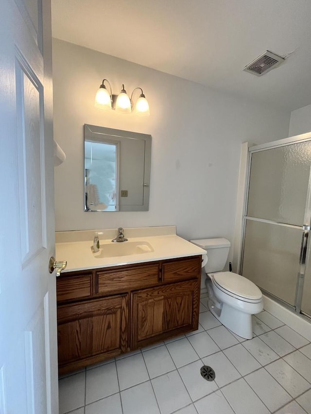 bathroom featuring tile floors, toilet, vanity, and an enclosed shower