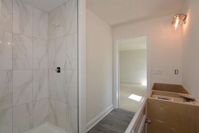 bathroom featuring tiled shower and wood-type flooring