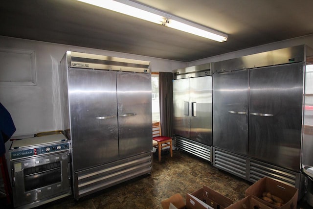 kitchen featuring stainless steel built in refrigerator and dark tile flooring