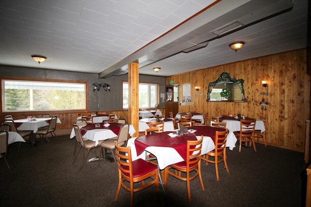 dining area with carpet floors, wood walls, and a wealth of natural light