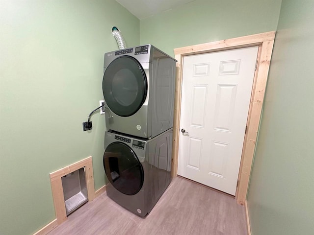 laundry room with light wood-type flooring and stacked washer and dryer