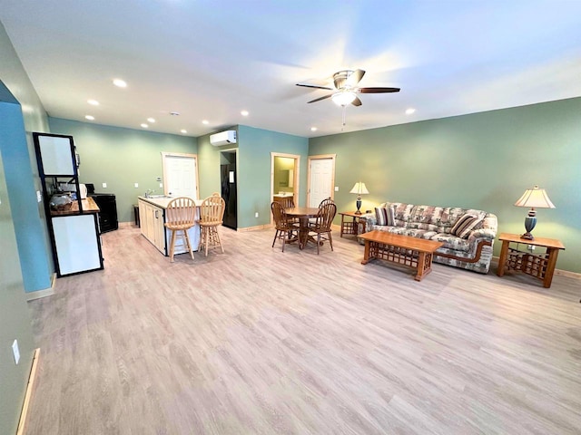 living room with an AC wall unit, ceiling fan, and light hardwood / wood-style floors