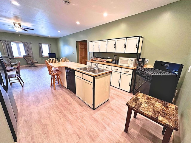 kitchen with black appliances, sink, light wood-type flooring, a kitchen island, and white cabinetry