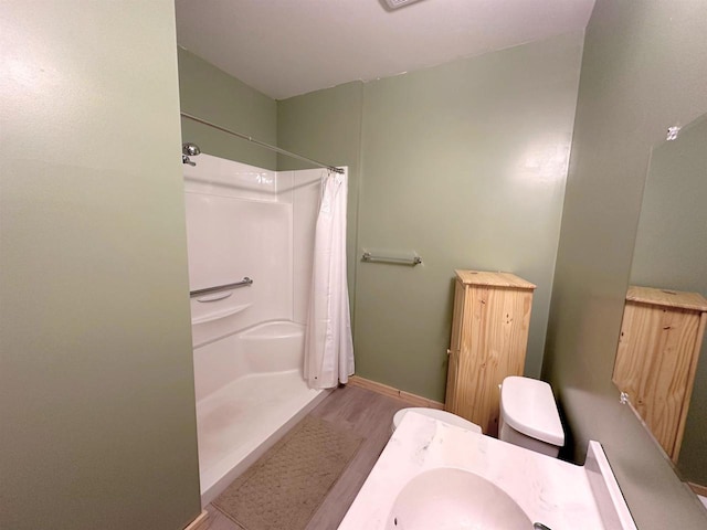 bathroom featuring a shower with shower curtain, wood-type flooring, and toilet