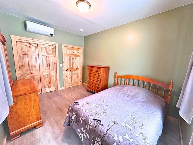 bedroom with wood-type flooring and a wall unit AC