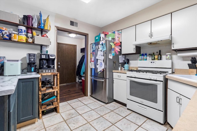 kitchen featuring stainless steel fridge, white gas stove, light tile floors, white cabinets, and tasteful backsplash