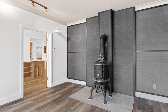 office area with track lighting, hardwood / wood-style floors, and a wood stove