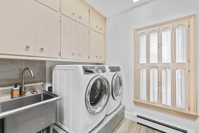 laundry area with light hardwood / wood-style flooring, cabinets, baseboard heating, washer and clothes dryer, and sink