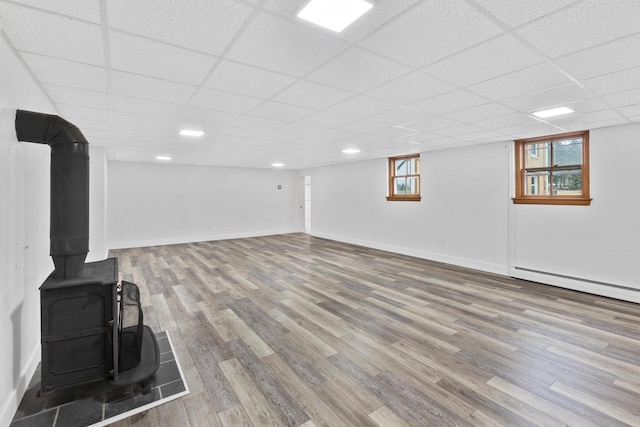 basement featuring hardwood / wood-style flooring, a healthy amount of sunlight, and a paneled ceiling