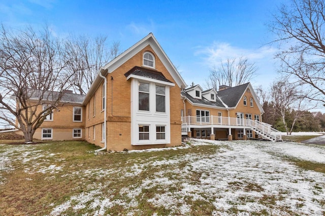 snow covered back of property with a wooden deck