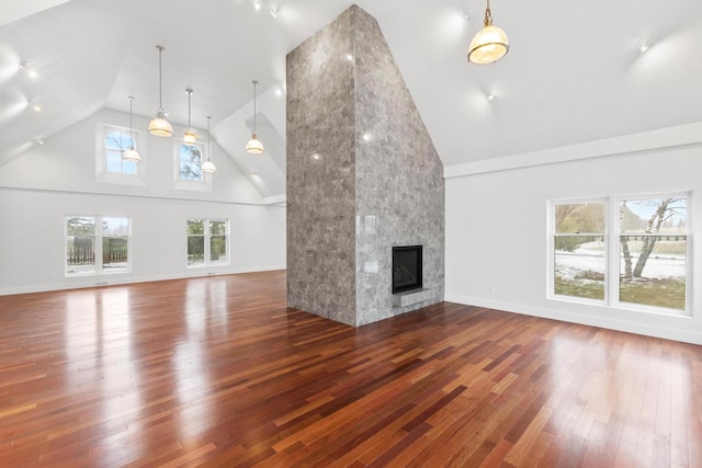 unfurnished living room with a wealth of natural light, wood-type flooring, and high vaulted ceiling