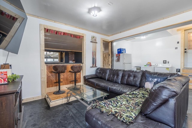 living room with bar, dark colored carpet, and washer and clothes dryer