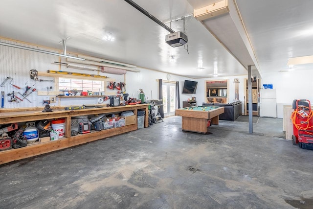 garage with white refrigerator, a garage door opener, and a workshop area