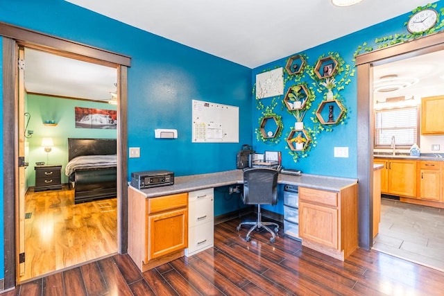 office with dark hardwood / wood-style flooring, built in desk, and sink