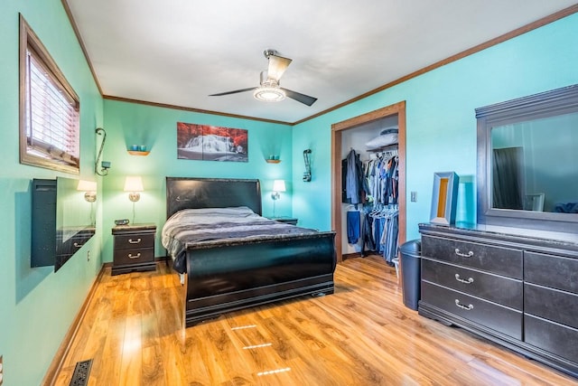 bedroom with ceiling fan, a closet, light hardwood / wood-style floors, a walk in closet, and crown molding