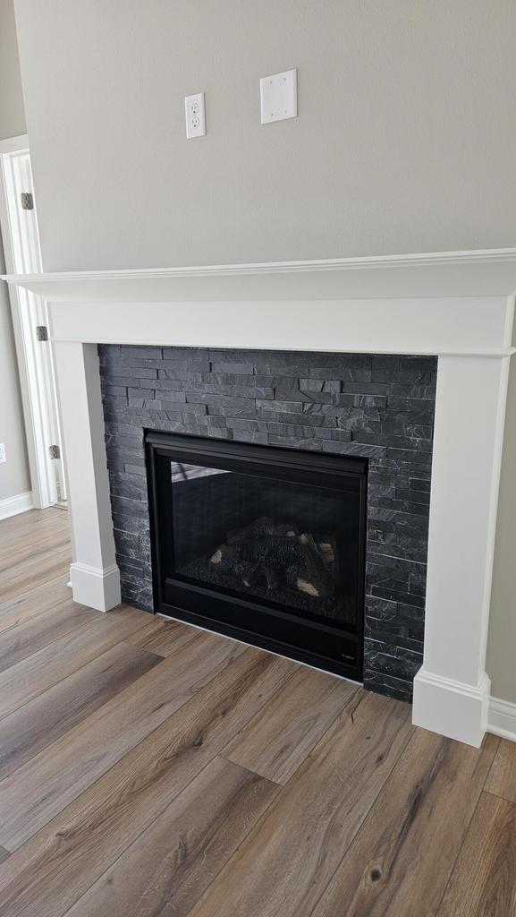 details with hardwood / wood-style flooring and a stone fireplace