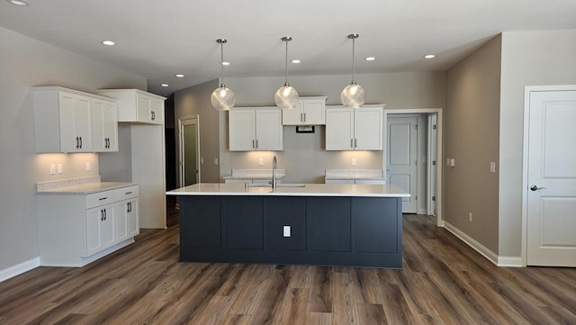 kitchen with a center island with sink, hanging light fixtures, white cabinets, dark hardwood / wood-style flooring, and sink