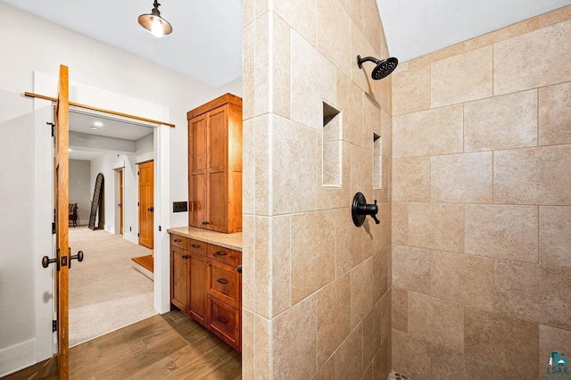 bathroom featuring vanity, a tile shower, and wood-type flooring