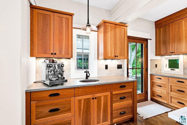 kitchen with decorative light fixtures, tasteful backsplash, dark wood-type flooring, and sink