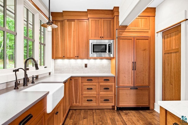 kitchen with decorative light fixtures, sink, tasteful backsplash, dark hardwood / wood-style flooring, and built in appliances