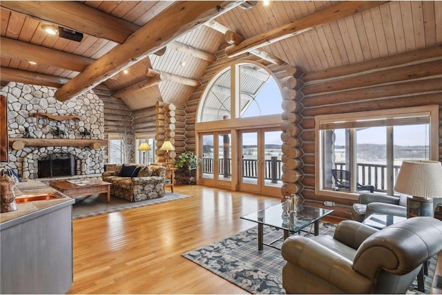 living room with wooden ceiling, a stone fireplace, light wood-type flooring, rustic walls, and french doors