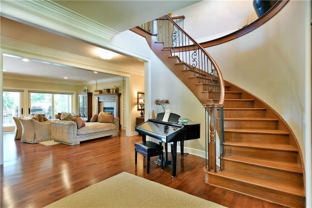 staircase with ornamental molding and dark hardwood / wood-style flooring