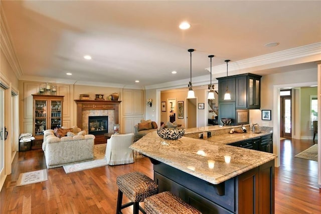 kitchen with dark hardwood / wood-style floors, a breakfast bar area, light stone counters, and crown molding