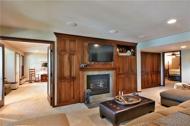 carpeted living room featuring ceiling fan and a tile fireplace