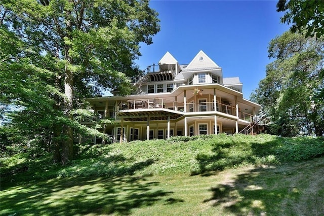 rear view of property with a balcony and a lawn