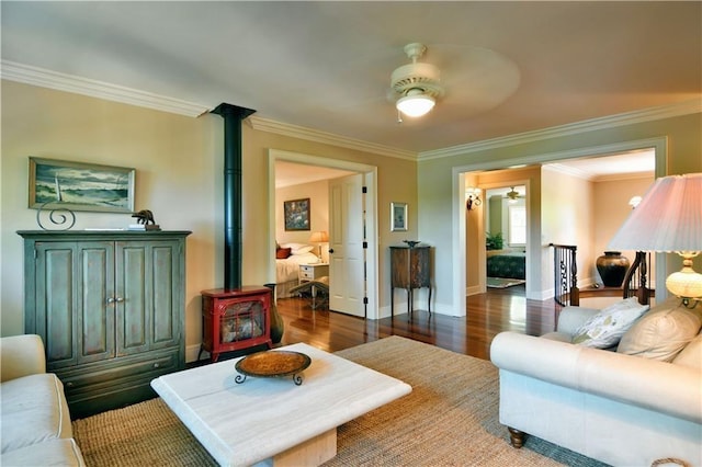 living room featuring ceiling fan, a wood stove, ornamental molding, and hardwood / wood-style floors