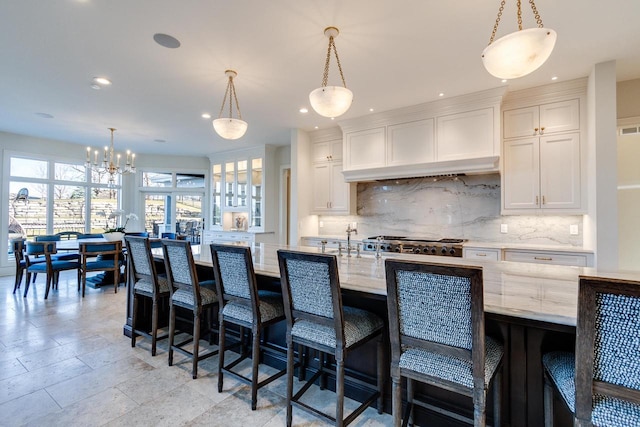 9809 Trappers Trl, Middleton, WI 53562 - kitchen with light stone countertops, a kitchen breakfast bar, white cabinets, and decorative light fixtures