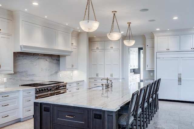 kitchen with white cabinets, backsplash, double oven range, and a center island with sink