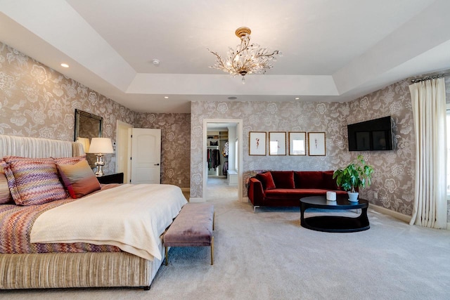 carpeted bedroom featuring a notable chandelier, a spacious closet, and a tray ceiling