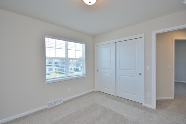 unfurnished bedroom featuring light colored carpet and a closet