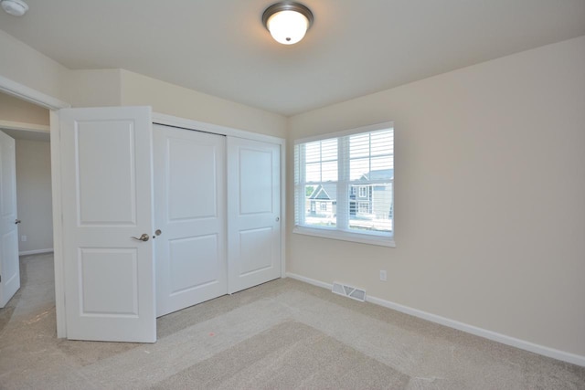 unfurnished bedroom featuring light colored carpet and a closet