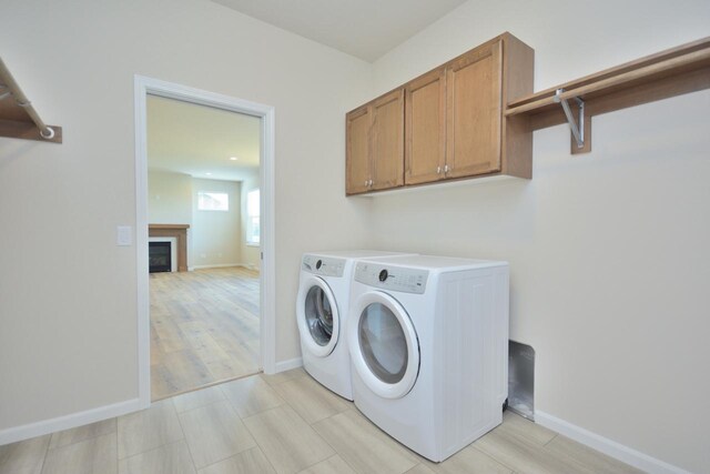 clothes washing area with cabinets and independent washer and dryer