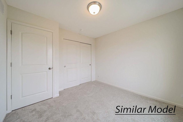 unfurnished bedroom with light colored carpet and a closet