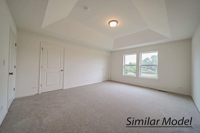 unfurnished room with a tray ceiling and carpet