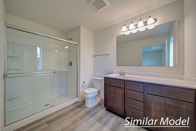 bathroom with vanity, hardwood / wood-style flooring, toilet, and a shower with shower door